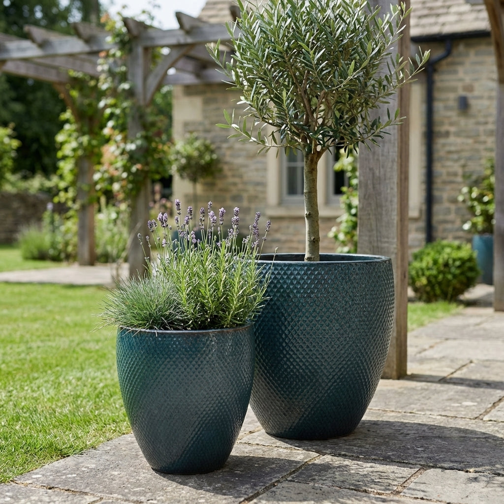 Petrolejově modrý keramický květináč Signac s buxusem v detailním záběru na moderní rodinné terase v jarním slunci.
