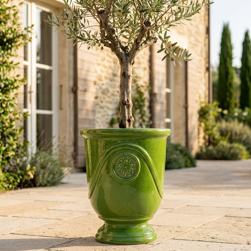 Detail jablečně zeleného keramického květináče Moliere s olivovníkem na slunné terase vily. Ručně vyráběný glazovaný květináč z terakoty s ozdobným reliéfem.