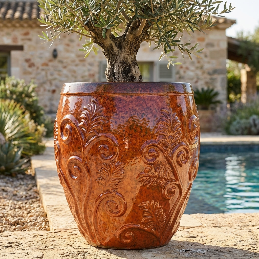 Detailní pohled na 85 cm vysoký Keramický květináč Gaia - Podzimní Oranžová s lesklou glazurou a olivovníkem na slunné kamenné terase u bazénu.