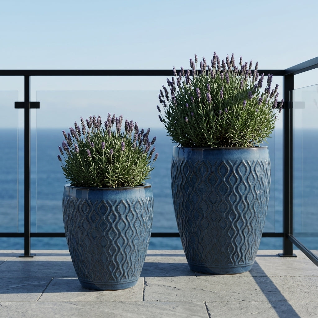 Detailní pohled na Doniczka ceramiczna Phenix - Antická modrá s rostlinou Cordyline na kamenné tarasie s výhledem na oceán.