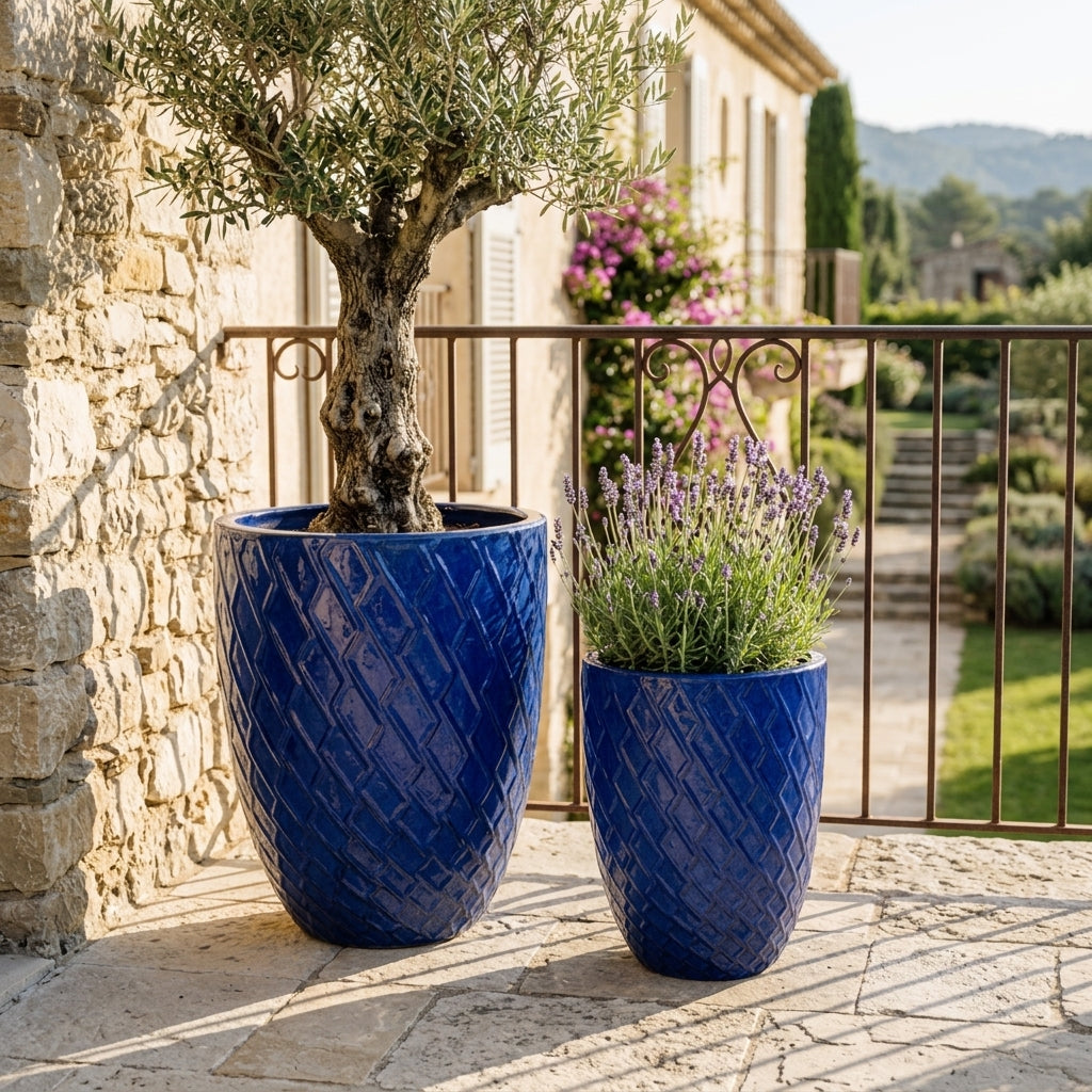 Detail velkého keramického květináče Zeus - Antická modrá s okrasným reliéfem a zasazeným olivovníkem na slunné kamenné terase.