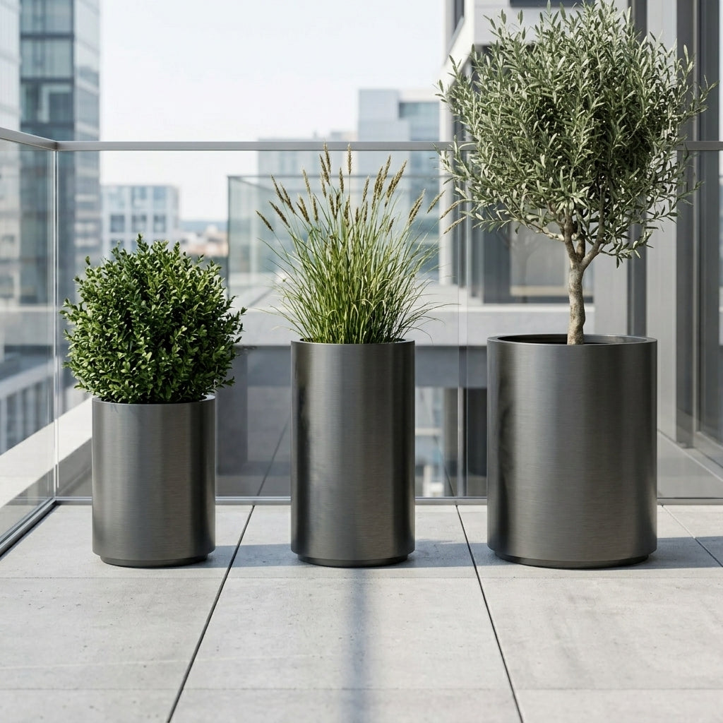 Detail na velký květináč z nerezové oceli Metropole v matně černé barvě s olivovníkem na moderní městské terase.