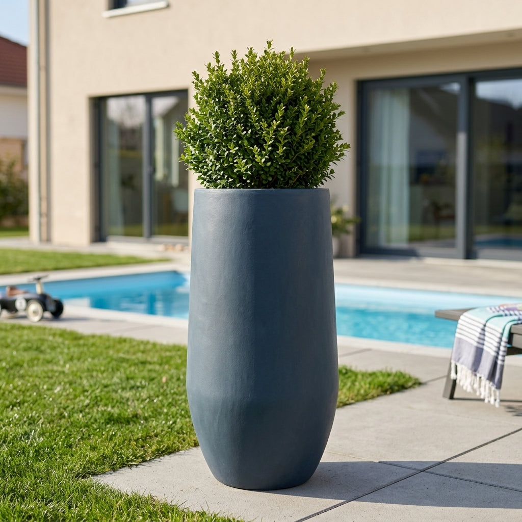 Detail tmavě šedého betonového květináče Zenith XXL (40 x 80 cm) s keřem na moderní terase s bazénem.