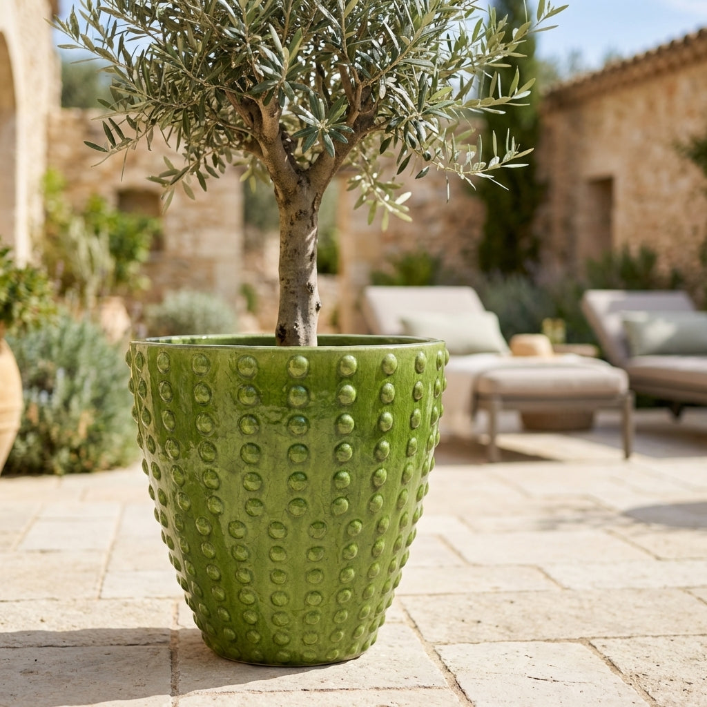 Ručně vyráběný glazurovaný keramický květináč Attila jablečně zelená z terakoty s výrazným reliéfem na slunné středomořské terase.