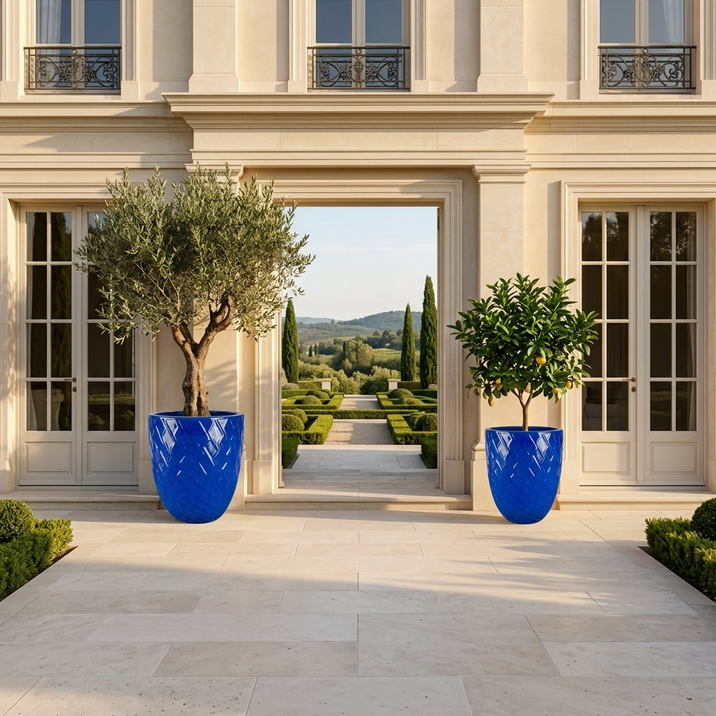 Detail velkého keramického květináče Zeus - Antická modrá s okrasným reliéfem a zasazeným olivovníkem na slunné kamenné terase.