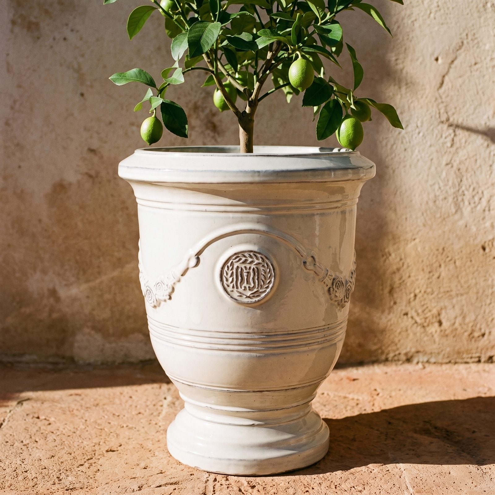 Detal ceramicznej donicy RICHELIEU Kremowa z girlandą i pieczęcią na kamiennym murku nad morzem
