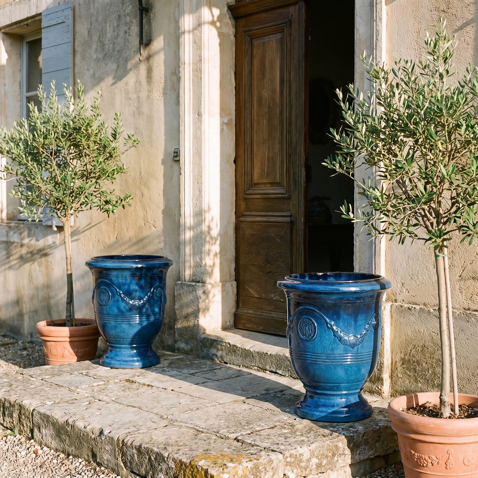 Dwie donice RICHELIEU Błękit lazurowy z drzewkami oliwnymi po bokach hotelowych drzwi na Riwierze